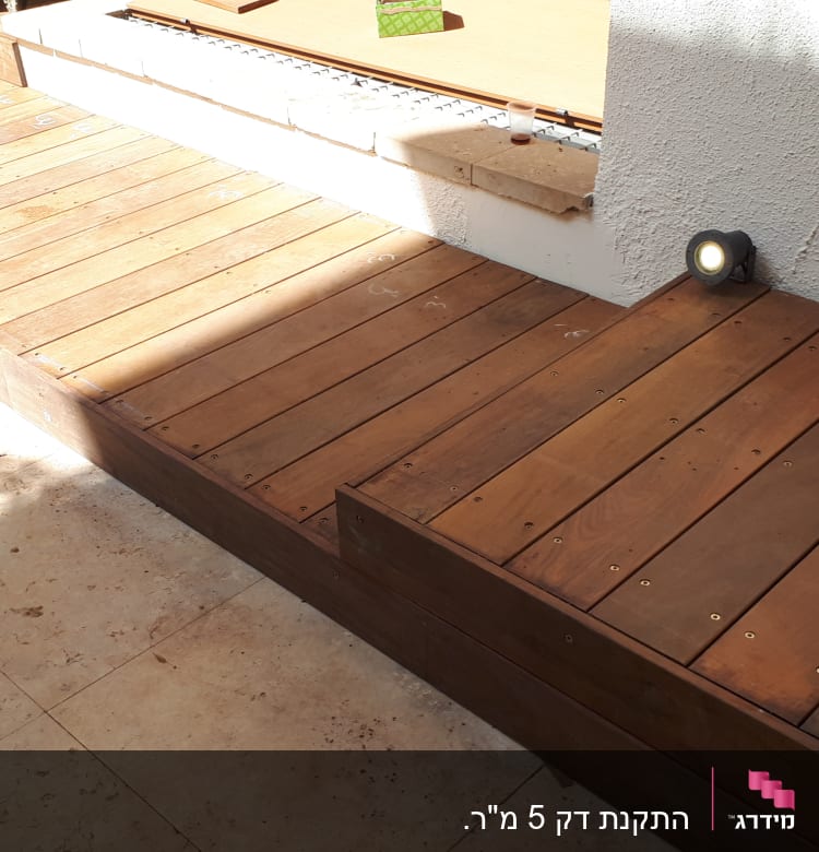 דק עץ עם תאורה מובנית ליד קיר לבן